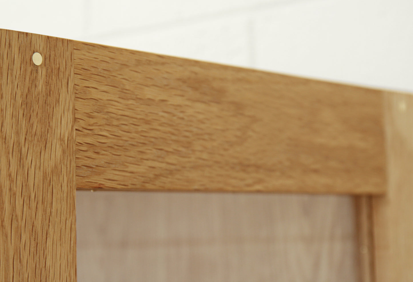 Up close image featuring white oak display cabinet with brass dowels.