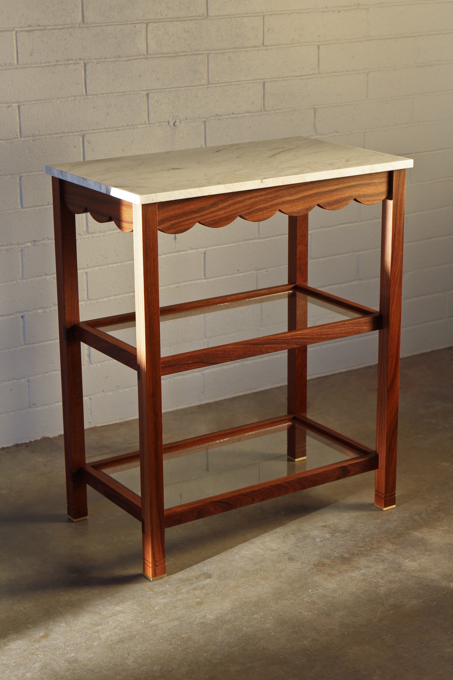 Custom wood serving table with marble top against a brick wall
