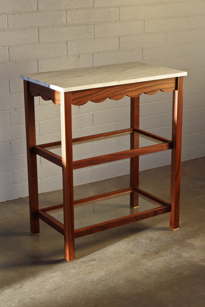 Custom wood serving table with marble top against a brick wall