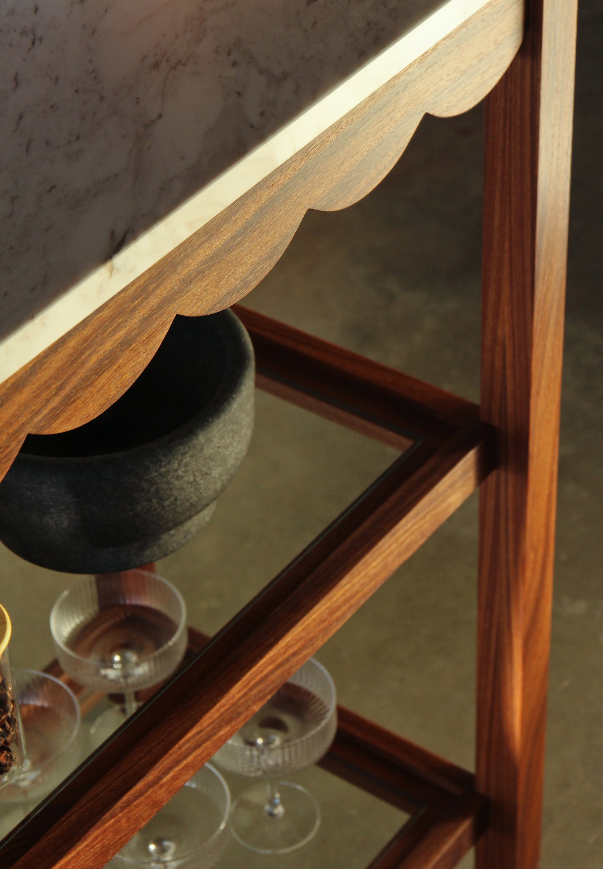 Wooden shelf with glassware and a vase on a reflective surface